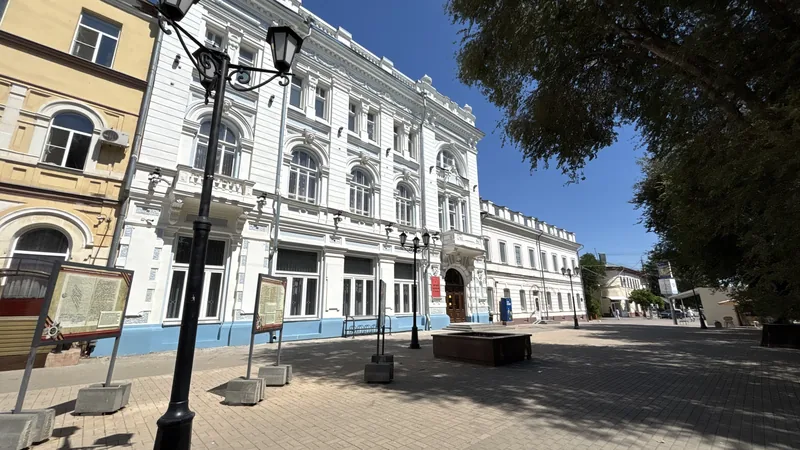 Музей боевой славы: фасад здания с лепниной, вид с площади, рядом фонари и деревья.