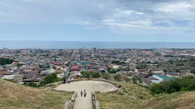 Панорама Дербента со смотровой площадки: черепичные крыши старого города спускаются к Каспийскому морю, вдали новостройки
