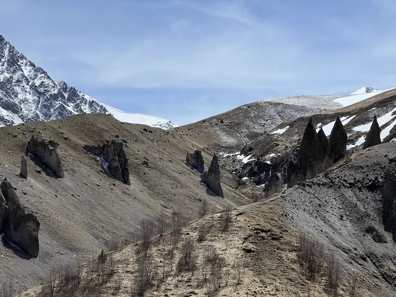 Каменные скалы-останцы на склоне по дороге к Джилы-Су, вдали заснеженные вершины