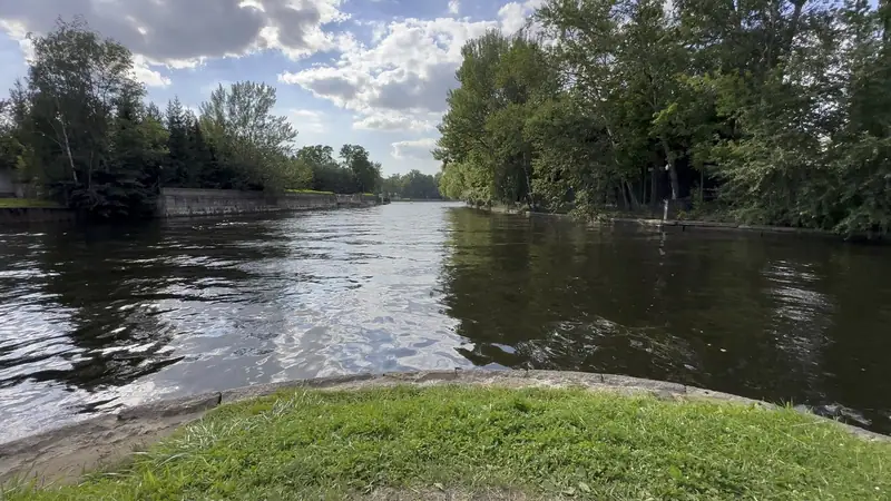 Протока Елагина острова между зелёными берегами, у воды старая гранитная стенка и трава