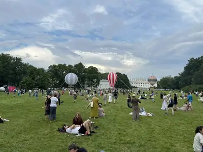 Люди отдыхают на большом лугу перед Елагиноостровским дворцом, в центре поля два декоративных аэростата