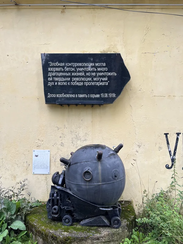 Форт Красная Горка: корпус морской мины у стены здания, над ним мемориальная доска с текстом о революционных событиях 1919 года.