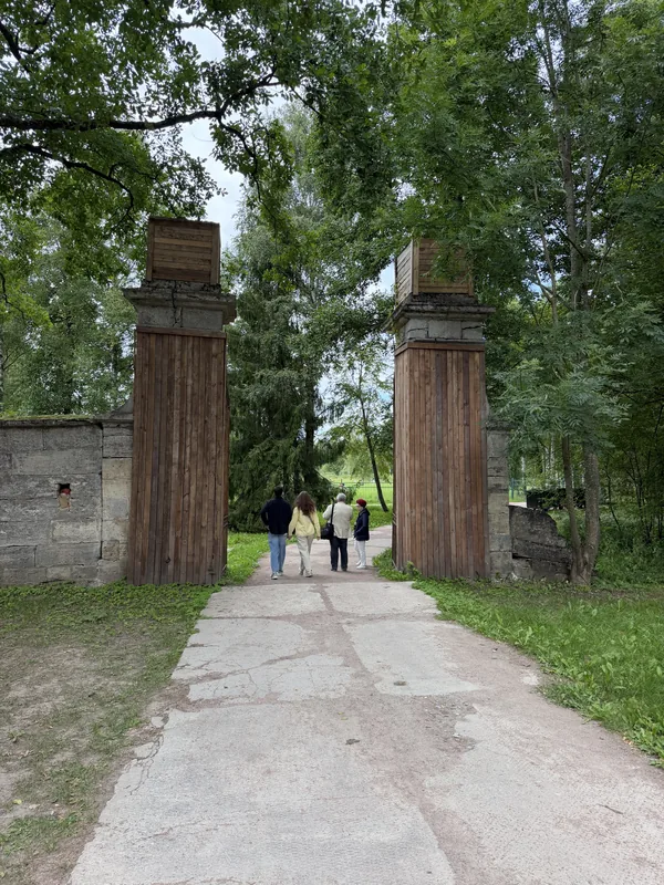Каменные пилоны ворот, за ними дорожка уходит в парк