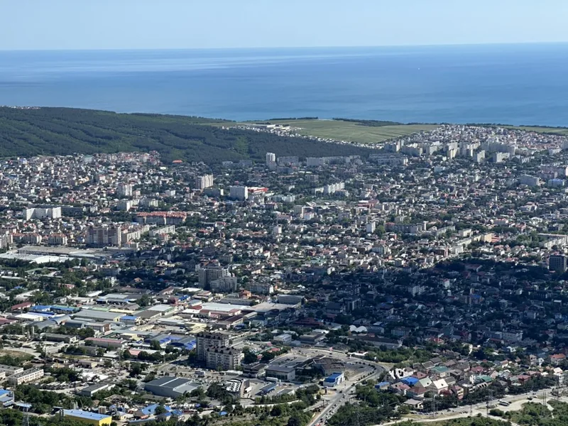 Геленджик: панорама города и бухты с высоты — плотная застройка спускается к морю и сосновому лесу на мысу.