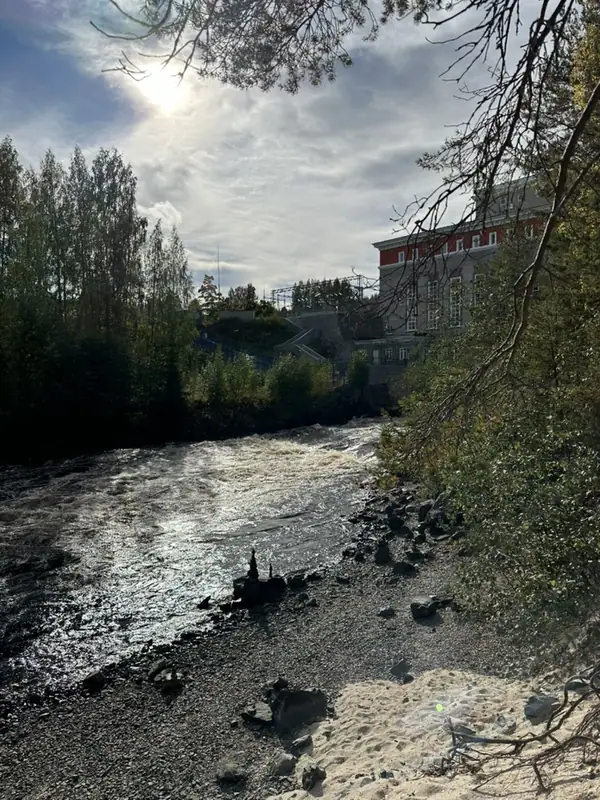 Поток воды по каменистому руслу реки в Гирвасе, на берегу — здание гидроэлектростанции
