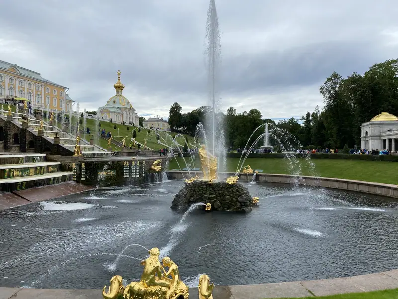 Фонтан «Самсон» с высокой струёй, за ним Большой Петергофский дворец в пасмурный день
