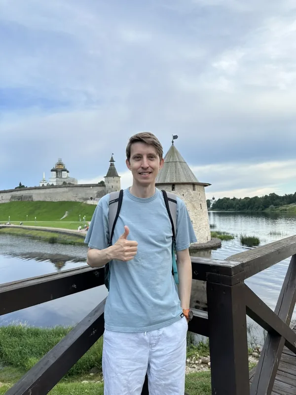 Автор TravelBelka на набережной напротив Псковского Крома: за спиной — стены и башни крепости на слиянии Псковы и Великой