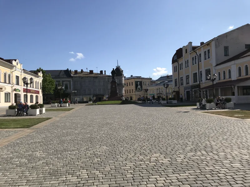 Просторная мощёная площадь с бронзовым памятником в центре, по сторонам двух- и трёхэтажные старинные дома