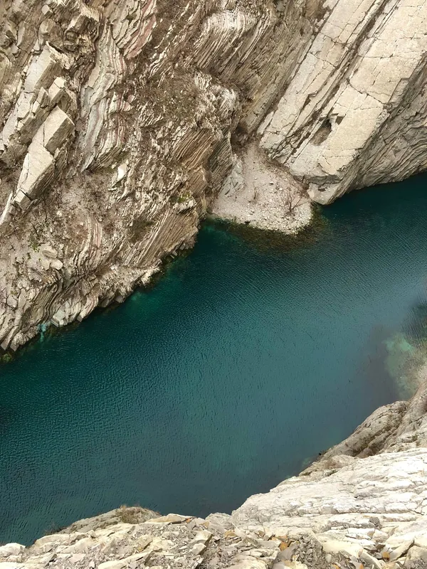 Бирюзовая вода Сулакского каньона с высоты, вдоль воды — светлые слоистые породы с наклонными пластами
