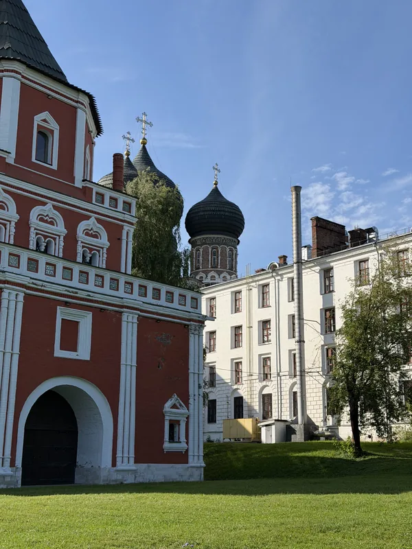 Мостовая башня с проездной аркой, за ней купола собора и белый корпус