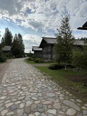 Булыжная дорога старой деревни между тёмными бревенчатыми избами