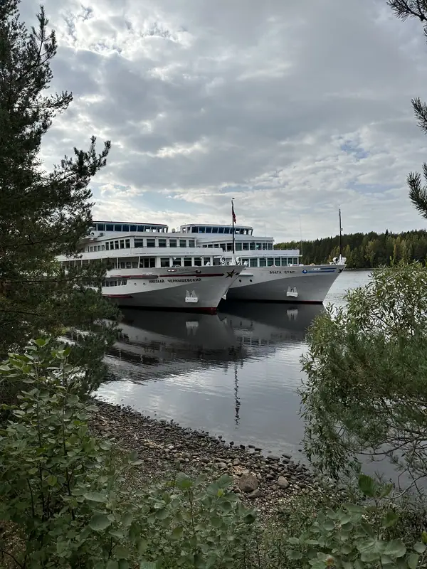 Два круизных теплохода стоят у берега Свири и отражаются в воде