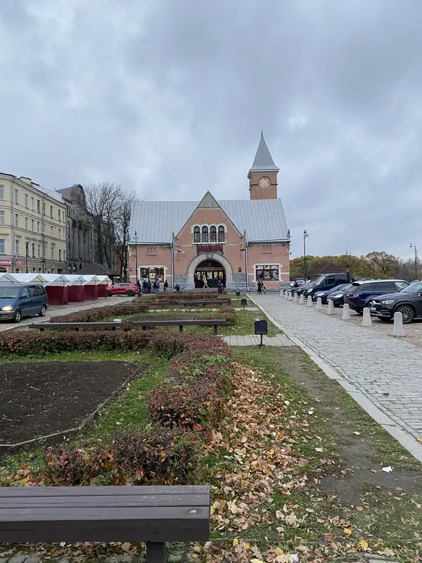 Краснокирпичное здание Выборгского рынка с часовой башенкой и сквер с опавшей осенней листвой