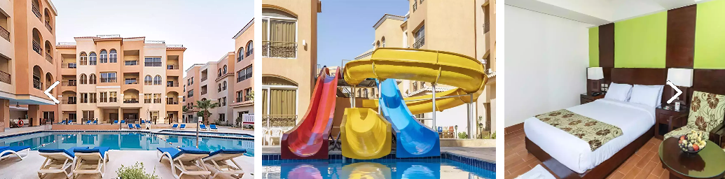 Resort-style pool area with lounge chairs, surrounded by peach-colored buildings and arches.